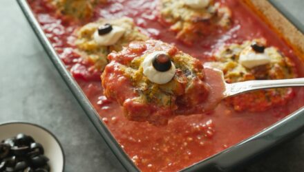 a baked fishball topped with mozzerella and olive to make a fish eyeball on a spoon