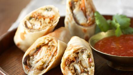 Pollock Spring Roll on a wooden plate with a red dipping sauce