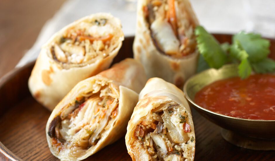 Pollock Spring Roll on a wooden plate with a red dipping sauce