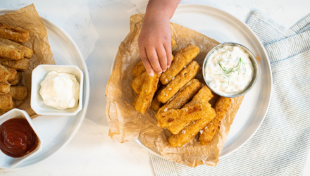 hand reaches for fish sticks on plate