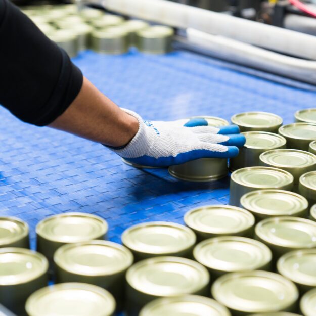 Arm sorting steel cans on blue table