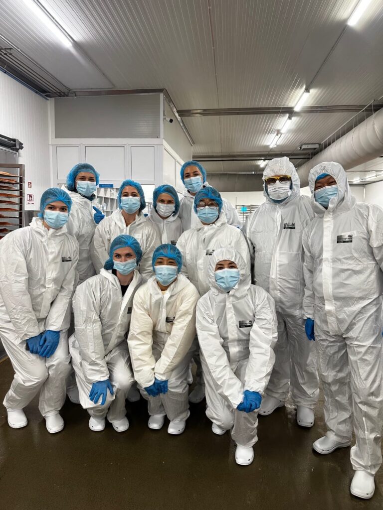 A group of people wearing white hazmat suits pose together.