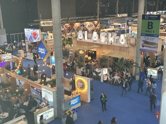 A busy conference hall with ALASKA displayed.