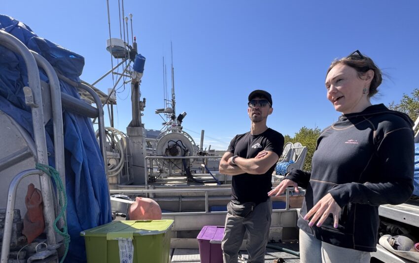 A man and a woman stand on the deck of a fishing boat.