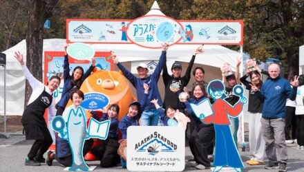 A group of people stand in front of the alaska seafood booth.